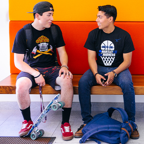 Two students talking with skateboard