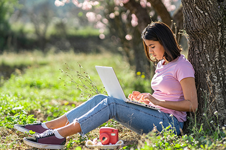 Student working on a laptop outdoors in springtime