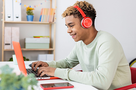 Student on laptop with headphones smiling