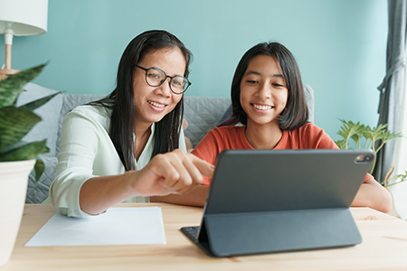 Student and parent smiling and viewing tablet